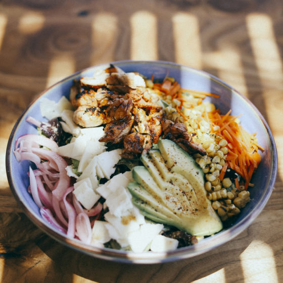 A Mexican inspired protein bowl from featuring chicken, avocado, onions, carrots and more.