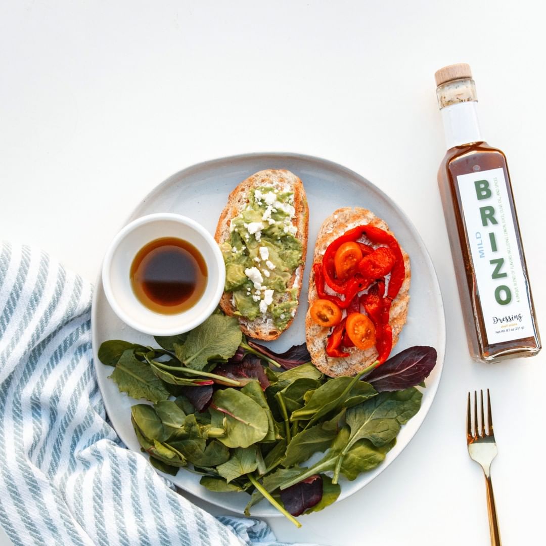 An example of the old Brizo Everything Dressing bottle next to a plate of spinach and toasts.