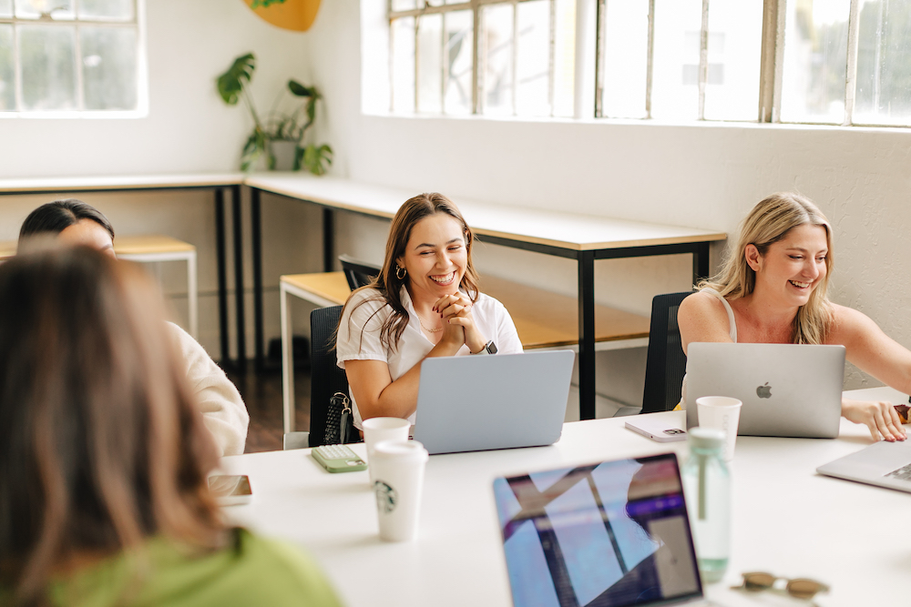 Women sitting at laptops laughing and working